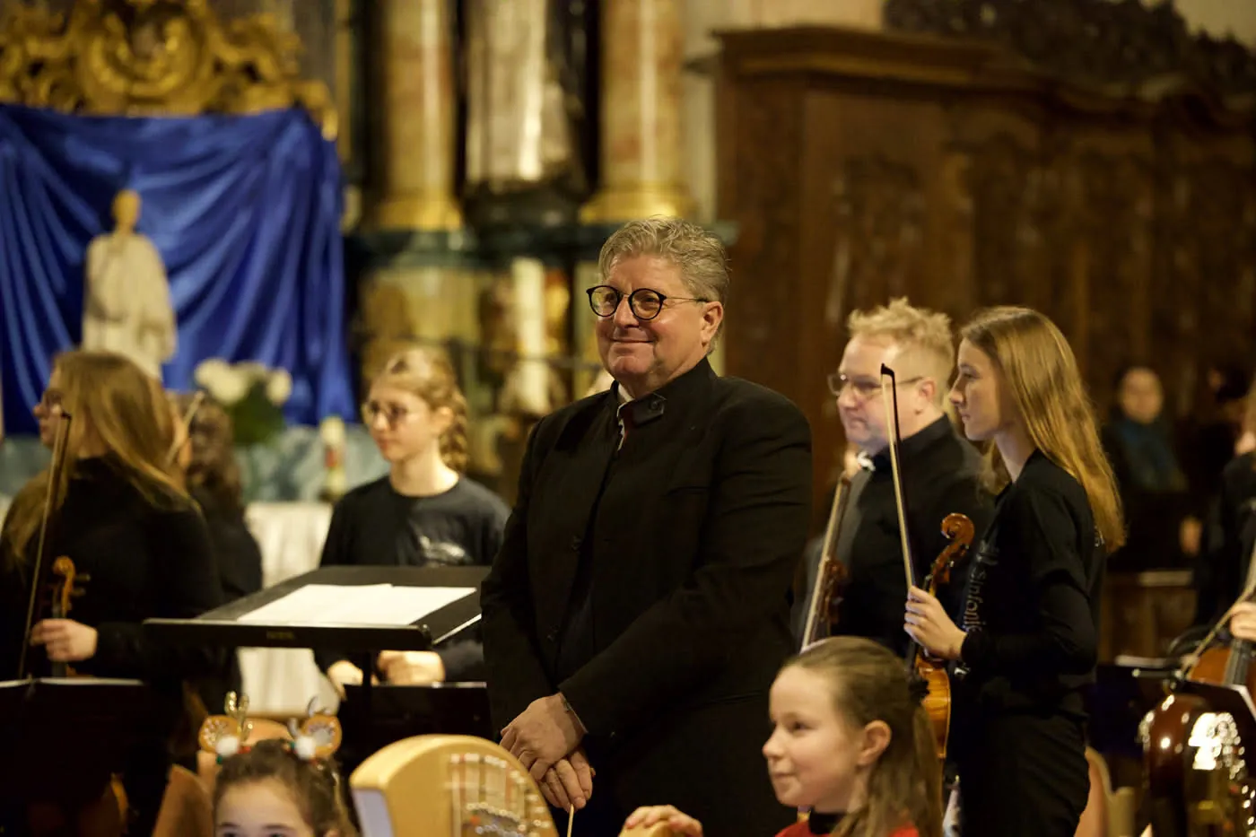 Schulleiter Marco Rogalski lächelt nach dem Konzert zwischen jungen Musikerinnen und Musikern