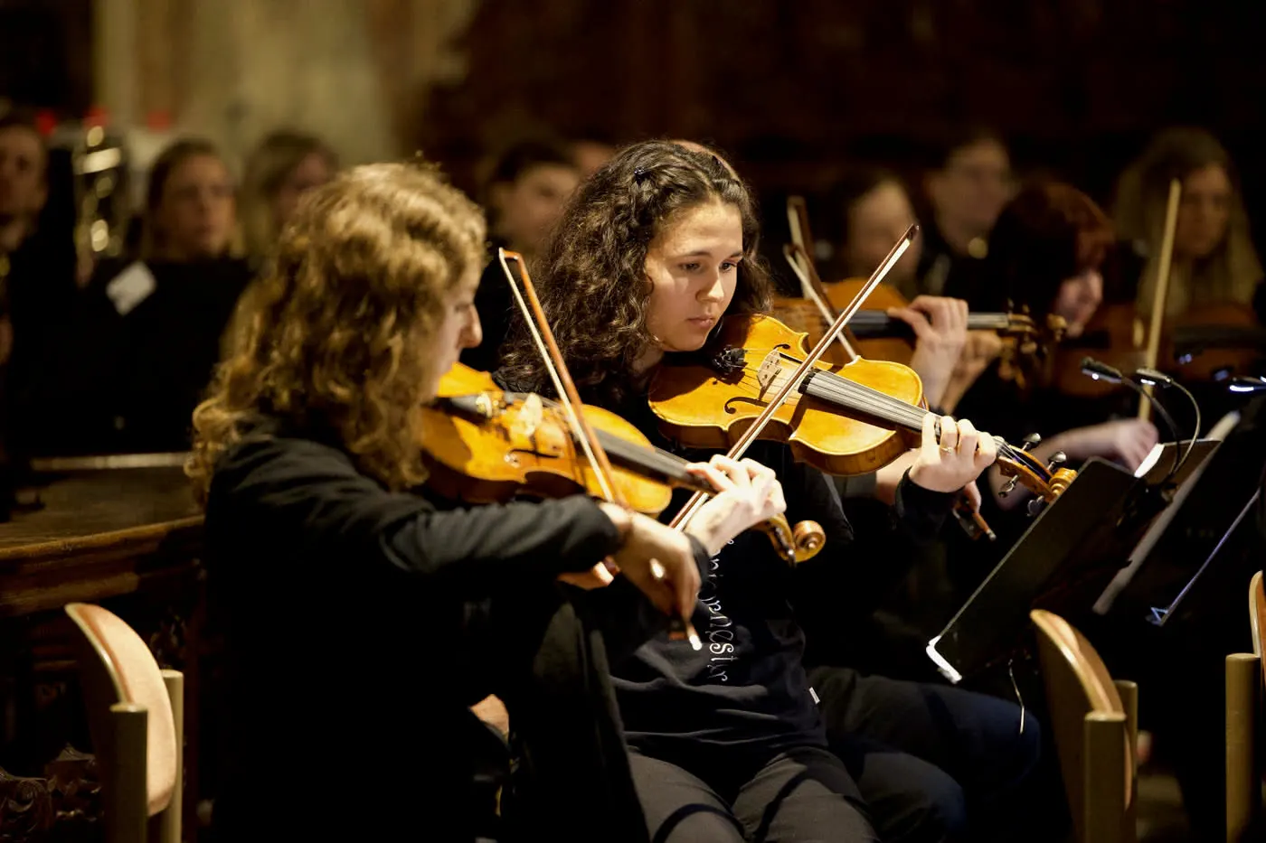 Zwei junge Geigerinnen spielen im Orchester in einer Kirche