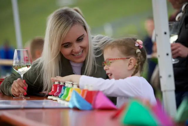 Eine Mutter und ihre Tochter probieren lachend bunte Glocken aus