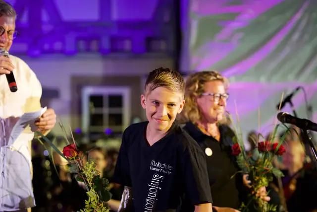 Ein Junge aus dem Sinfonieorchester strahlt nach dem Konzert, neben ihm Blumensträuße