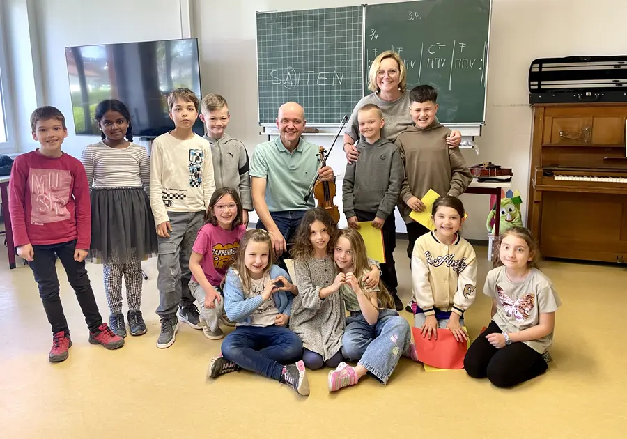 Eine Grundschulklasse mit ihrem Geigenlehrer im Musikraum